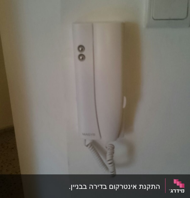 אינטרקום לבן עם שפופרת על קיר